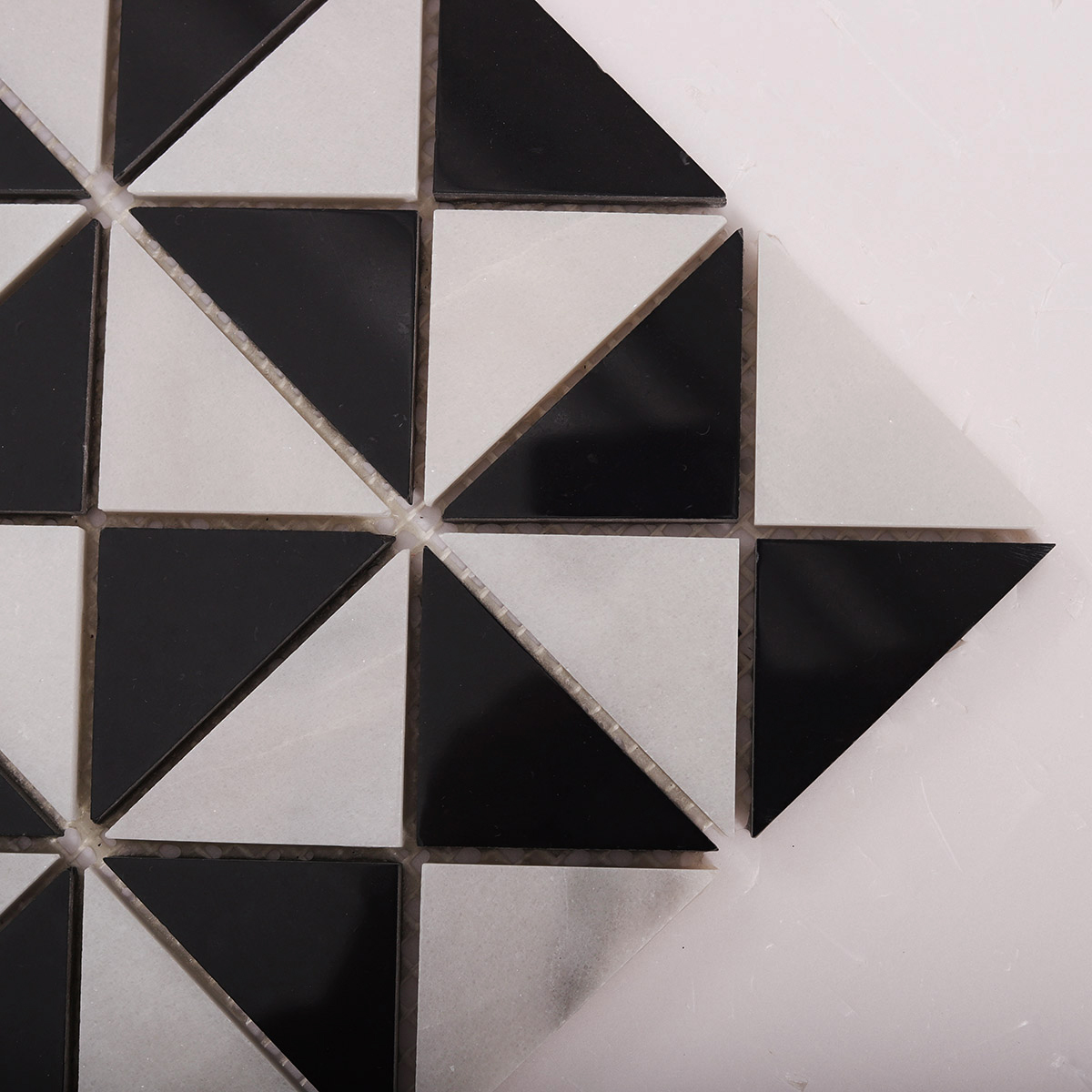 Close-up of Carrara White and Black Triangle Windmill marble mosaic tiles.
