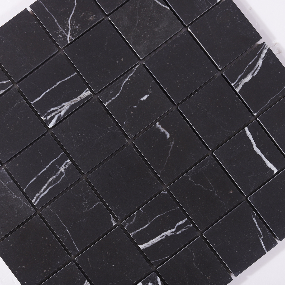 Close-up of the smooth surface and sleek finish of Nero Marquina black marble mosaic tiles.