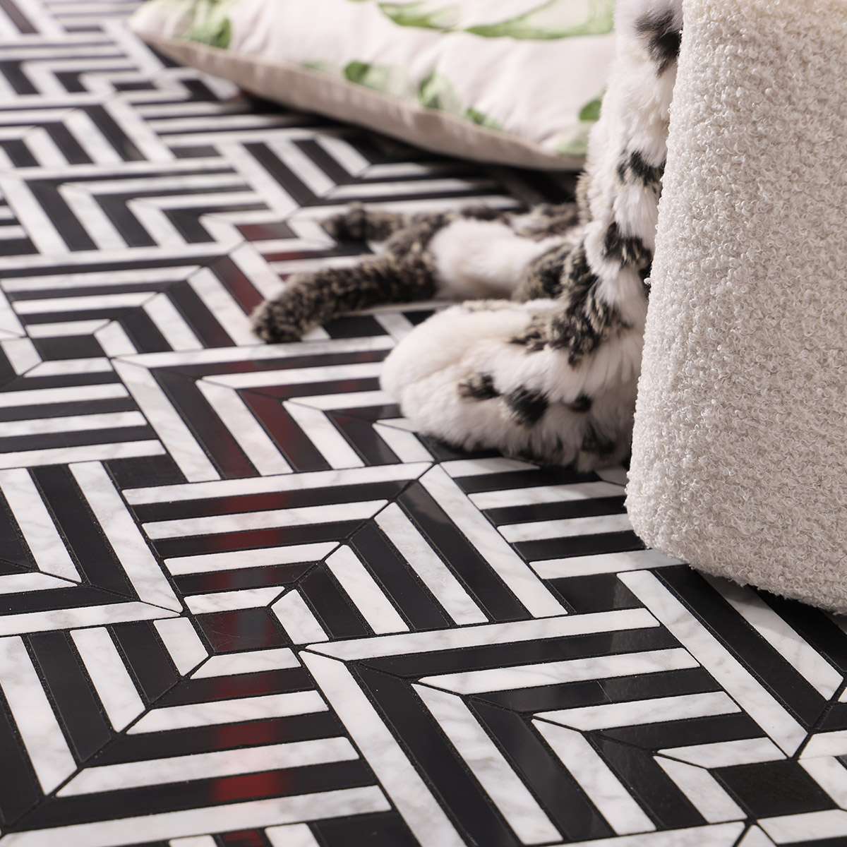 A cozy scene with a black and white geometric mosaic floor and a pillow.