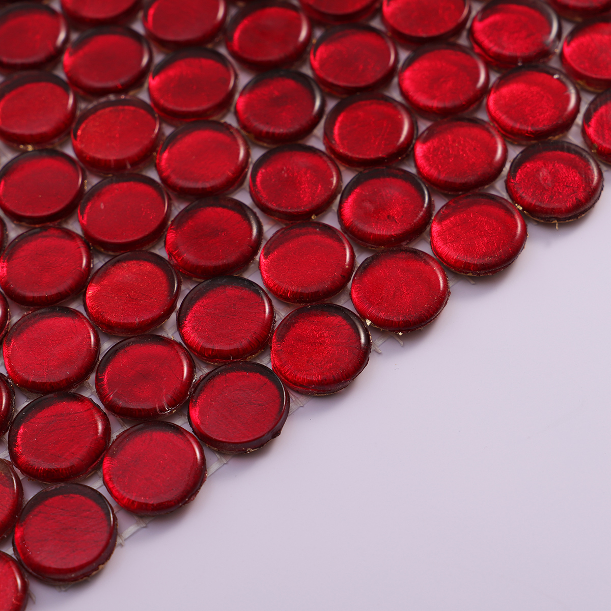 Side view of red glass circular mosaic tile, showcasing its thickness.