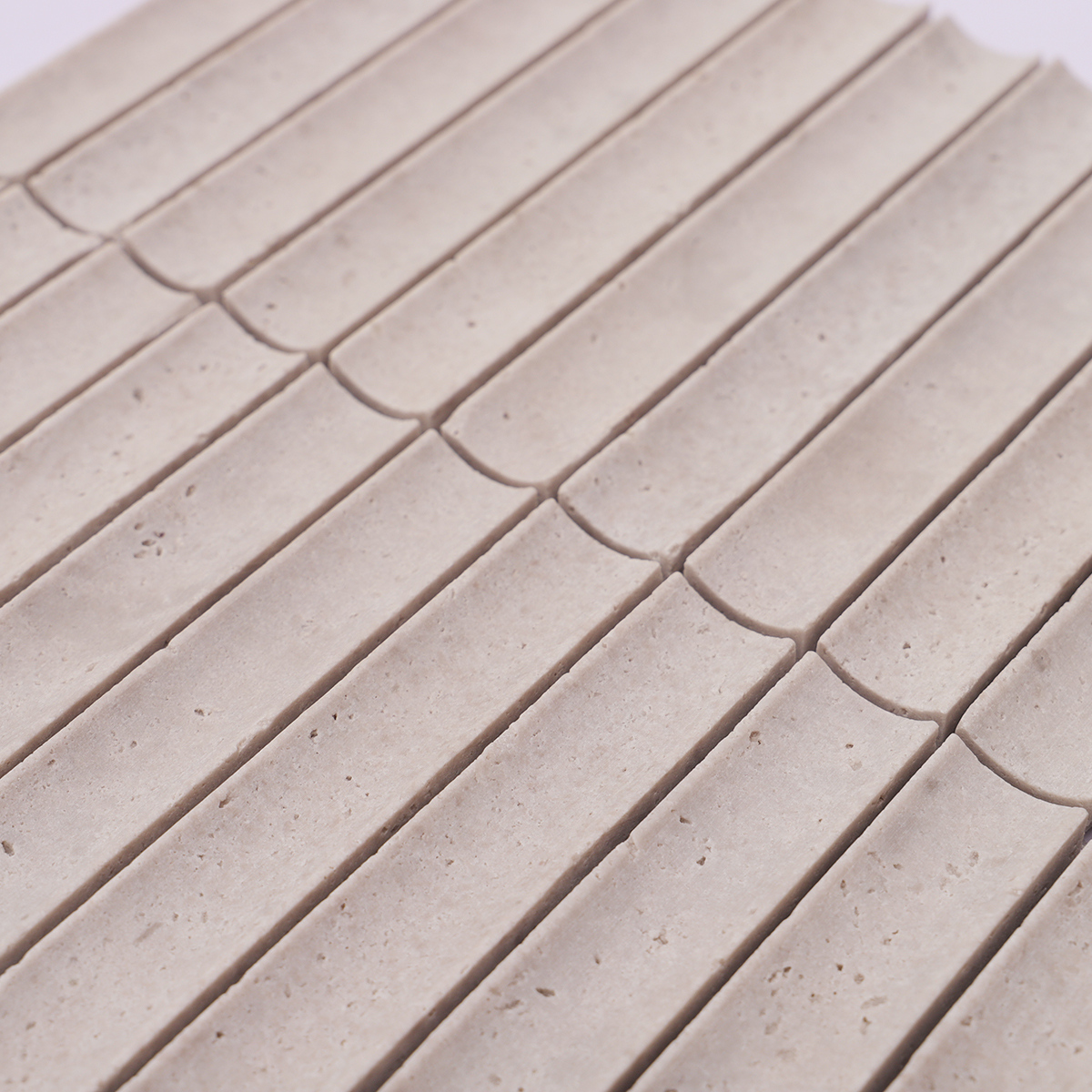 Detailed view of the surface texture of the gray travertine stone mosaic tile.
