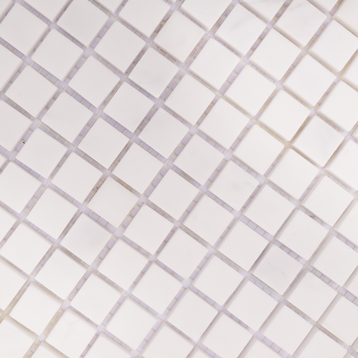 Close-up of the surface and shine of small square white polished marble mosaic tiles.