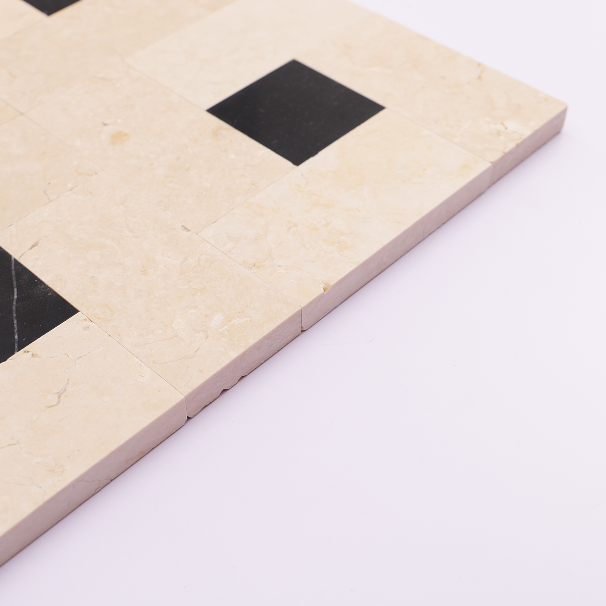 Side view showing the thickness of beige with black polished marble square mosaic tiles.