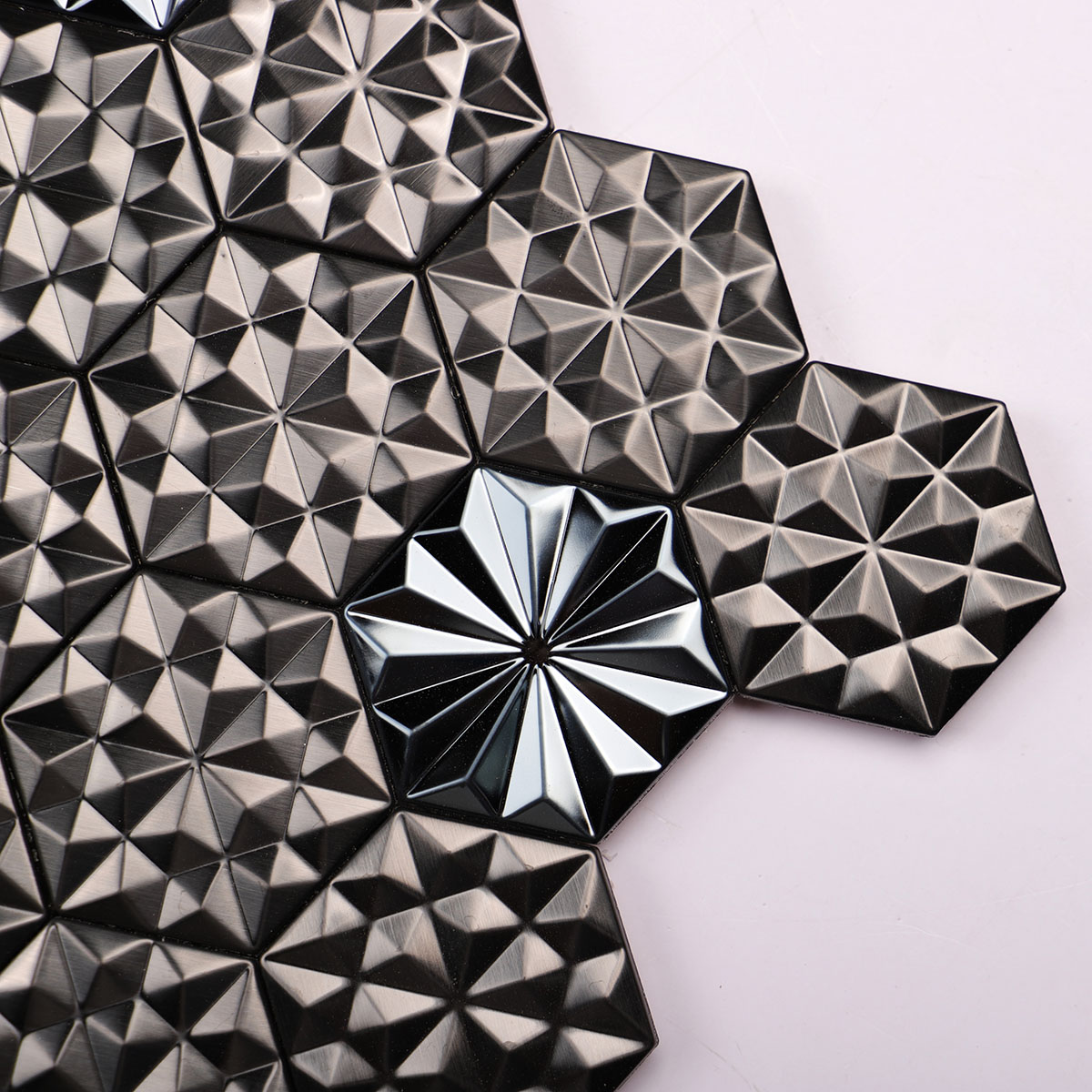 Macro close-up of black metal 3D groutless hexagon mosaic tile in stainless steel.