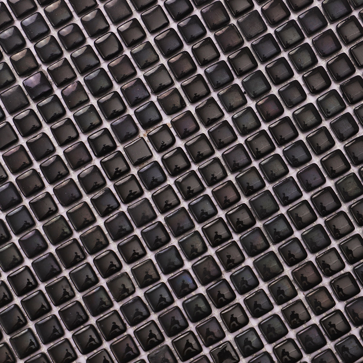 Detailed close-up of tiny black glossy recycled glass mosaic tiles.