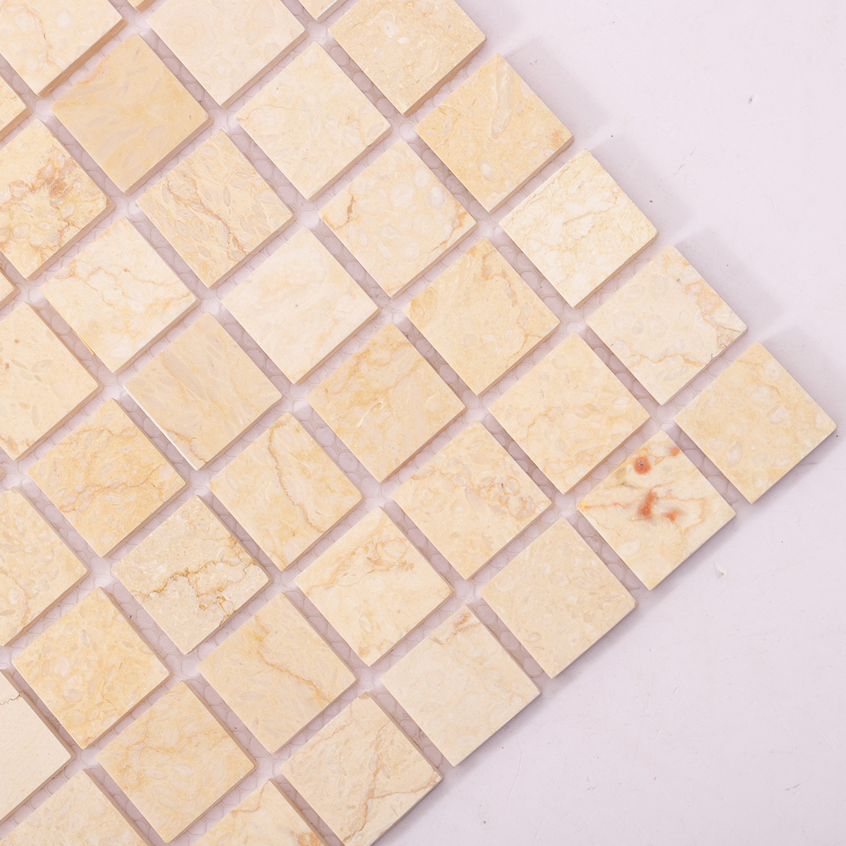 Detailed close-up of Crema Marfil square marble mosaic tiles.