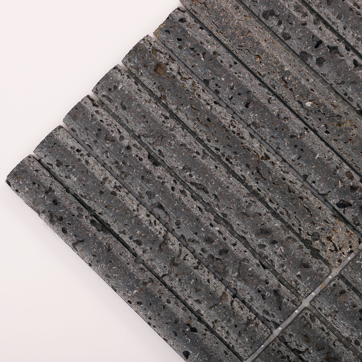 Detailed close-up of 3D concave fluted strip black lava stone mosaic tiles.