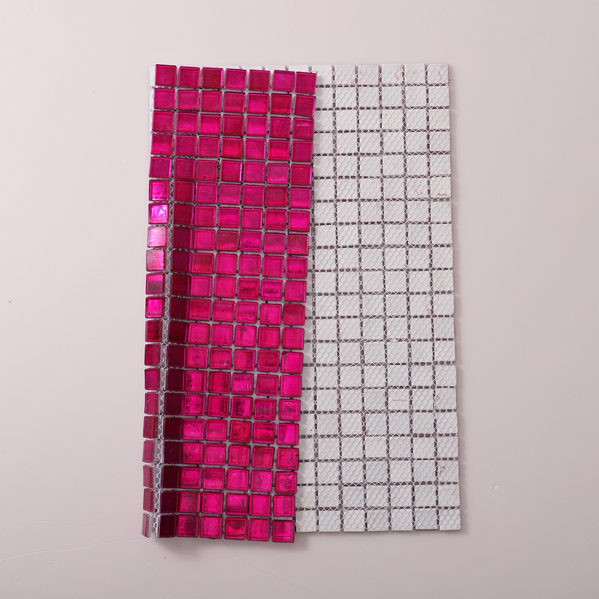 Folded back side of dark pink foil glossy square glass mosaic tiles.