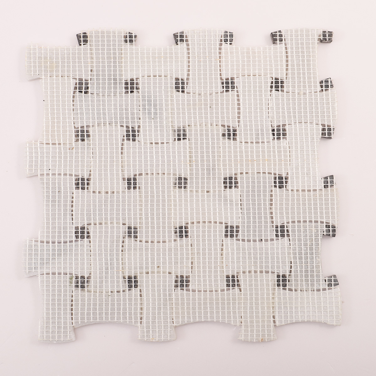Back side of Carrara white basketweave marble mosaic tiles with black dots