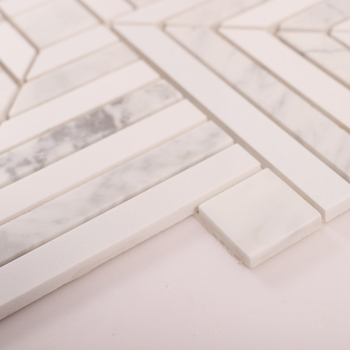 Side close-up view of white geometric marble mosaic tiles, showing texture and thickness.