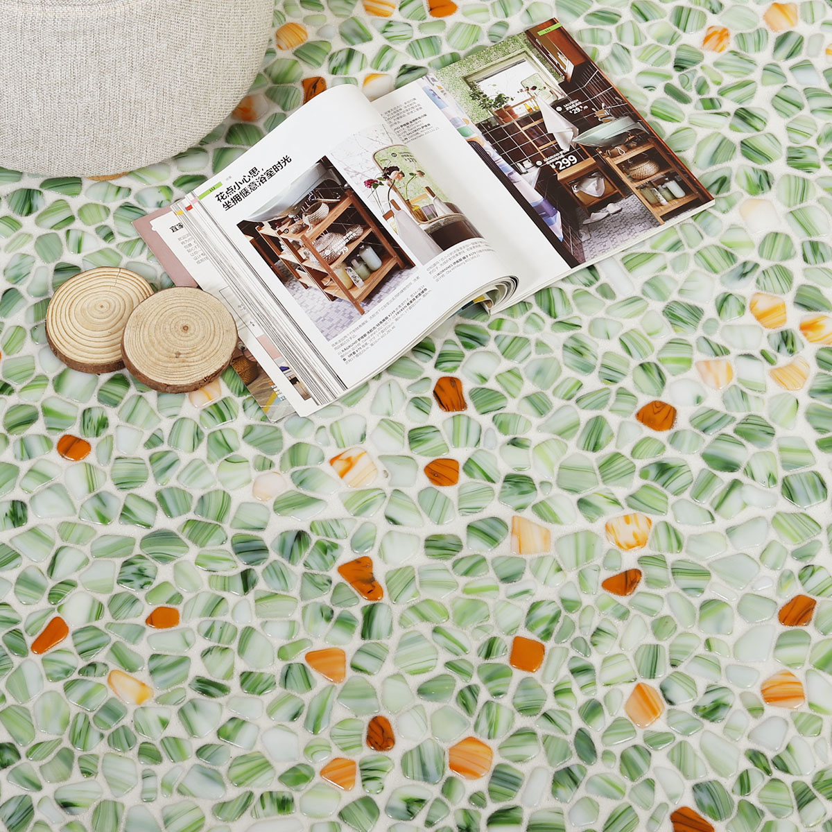 Green glass pebble mosaic tiles resembling river rocks next to a book.