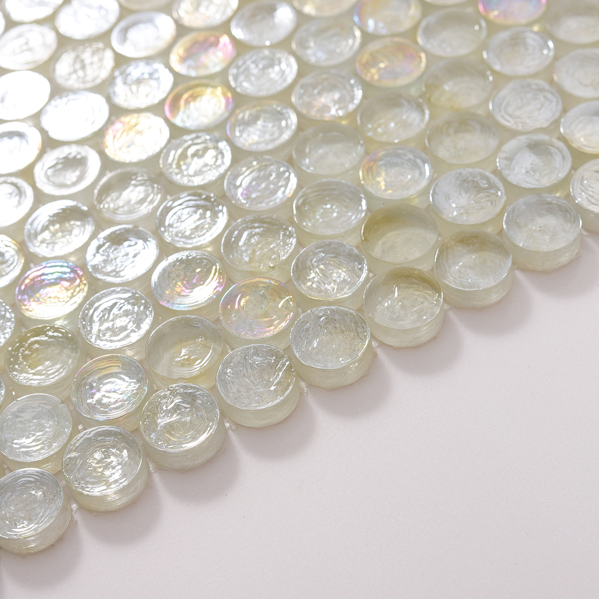 Side view close-up of White Iridescent Penny Round Glass Mosaic Tile, smooth edges visible