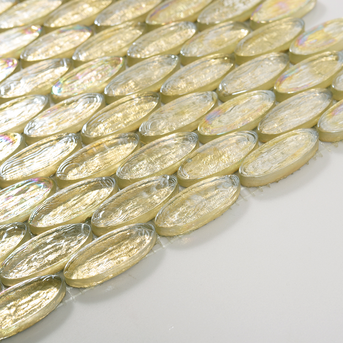 Side view close-up of Gold Foil Oval Glass Mosaic Tile, smooth edge detail visible