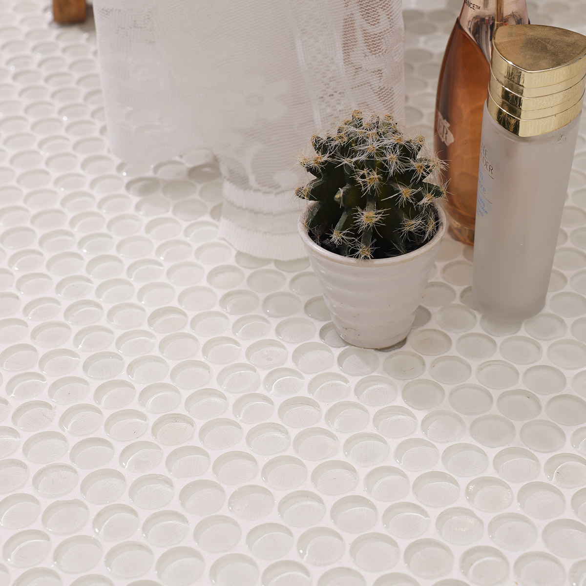 White circular mosaic tiles on the floor with a small plant and items.