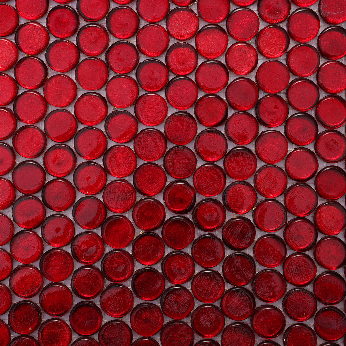 Close-up of red glass circular mosaic tiles, highlighting texture and gloss