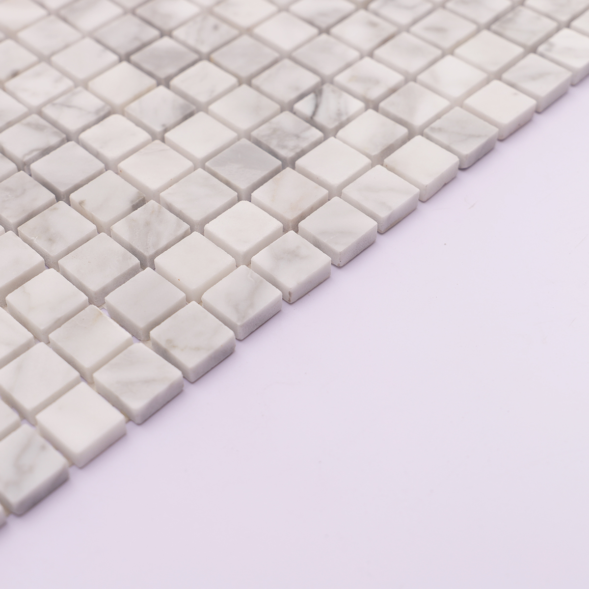 Side view showing the thickness of Carrara white honed marble square mosaic tiles.