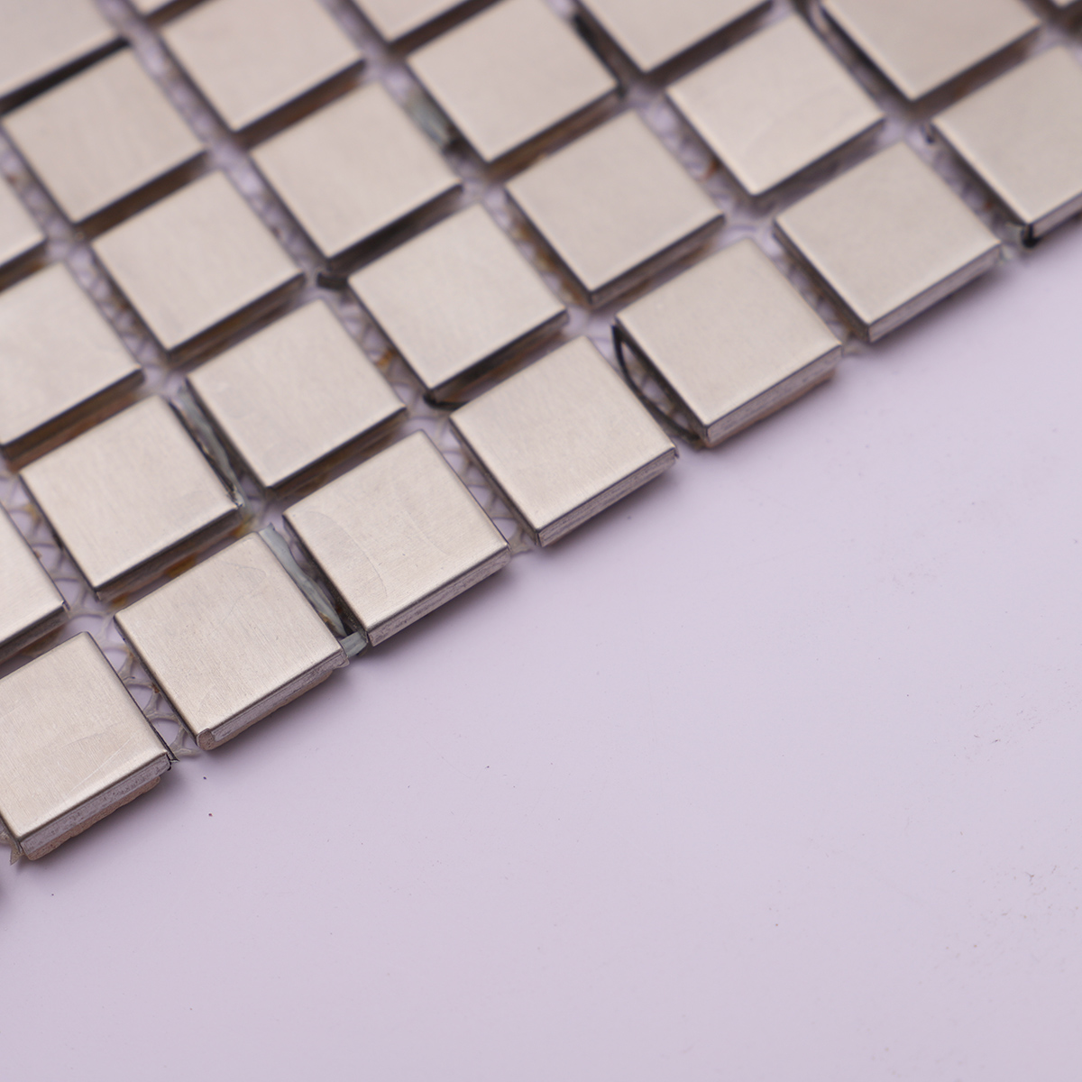 Side profile showing the thickness of brushed silver stainless steel mosaic tiles.
