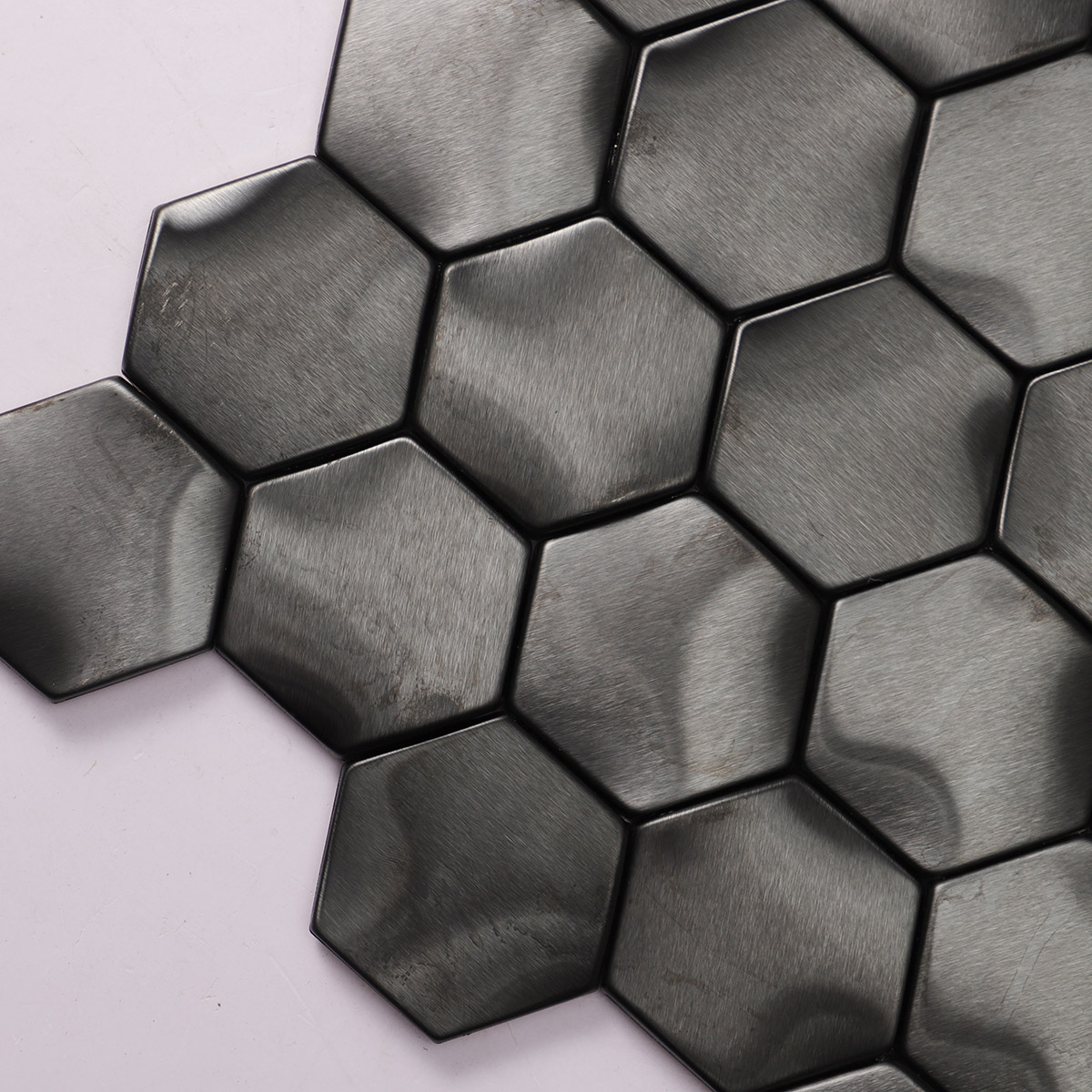 Detailed close-up of wavy 3D metal black brushed stainless steel hexagon mosaic tiles.