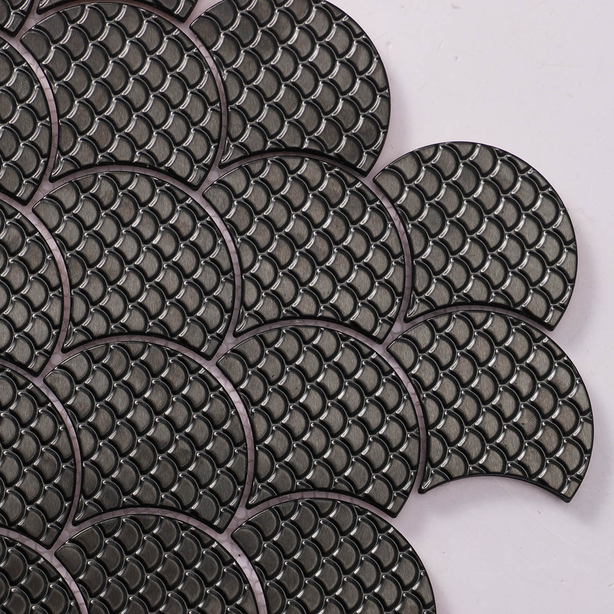 Texture close-up of black metal fish scale pattern mosaic tiles.