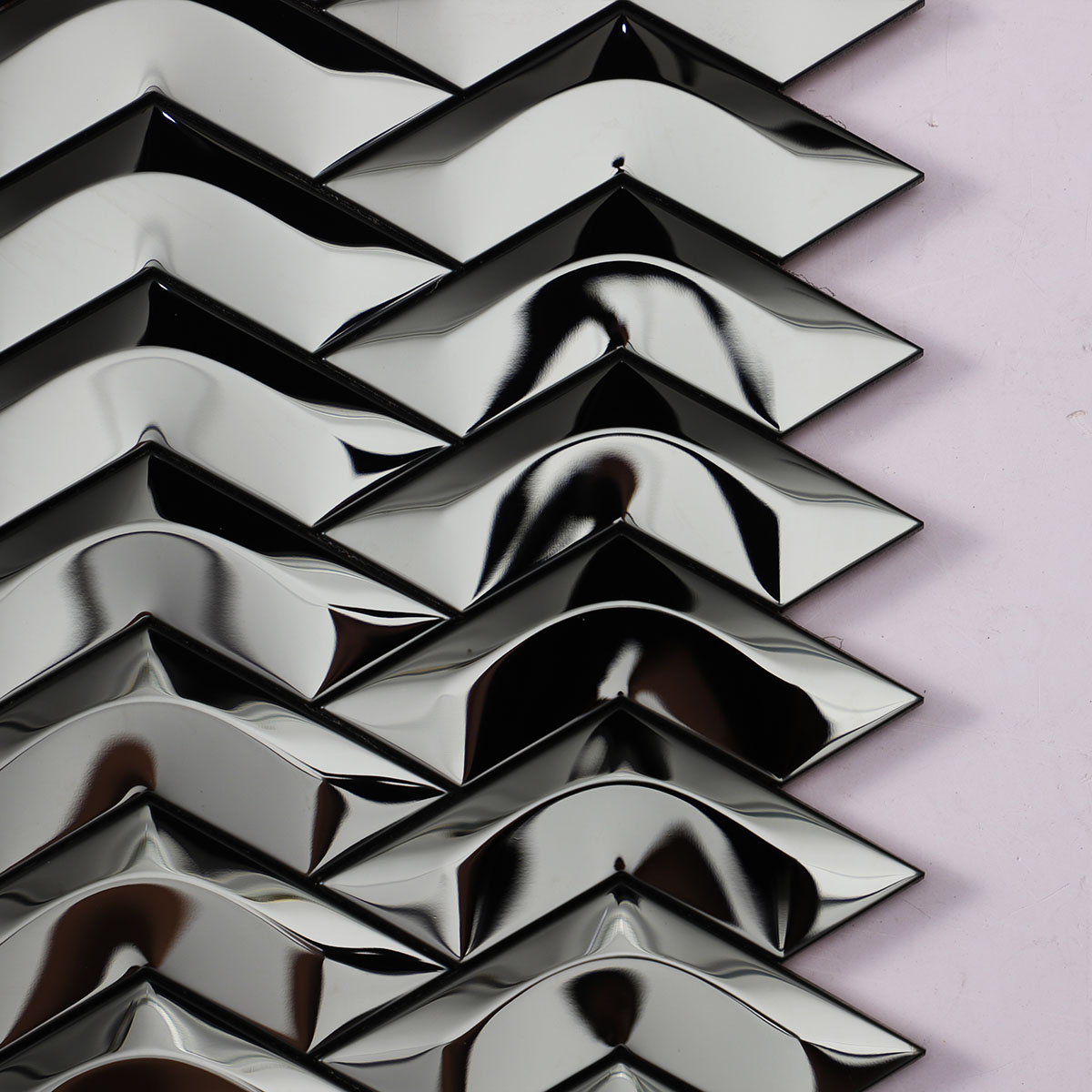 Close-up view of black stainless steel chevron 3D mirror mosaic tiles.