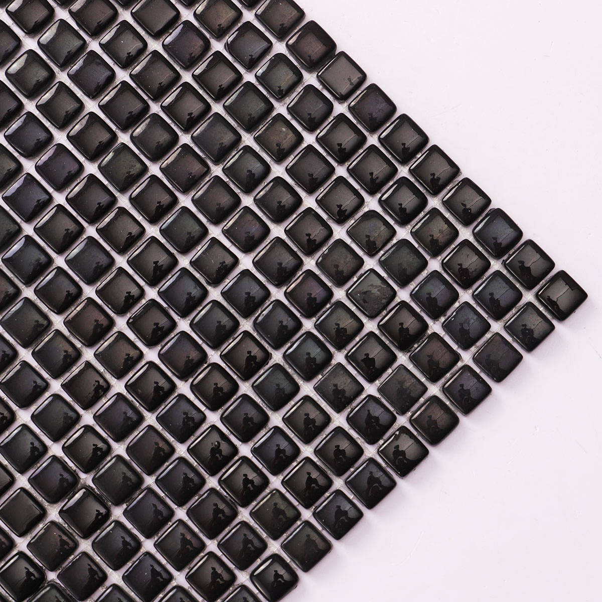 Close-up view of tiny black glossy recycled glass mosaic tiles.