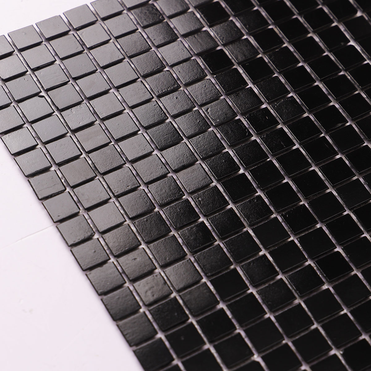 Detailed close-up of black square fired earth glass mosaic tiles 15mm x 15mm.