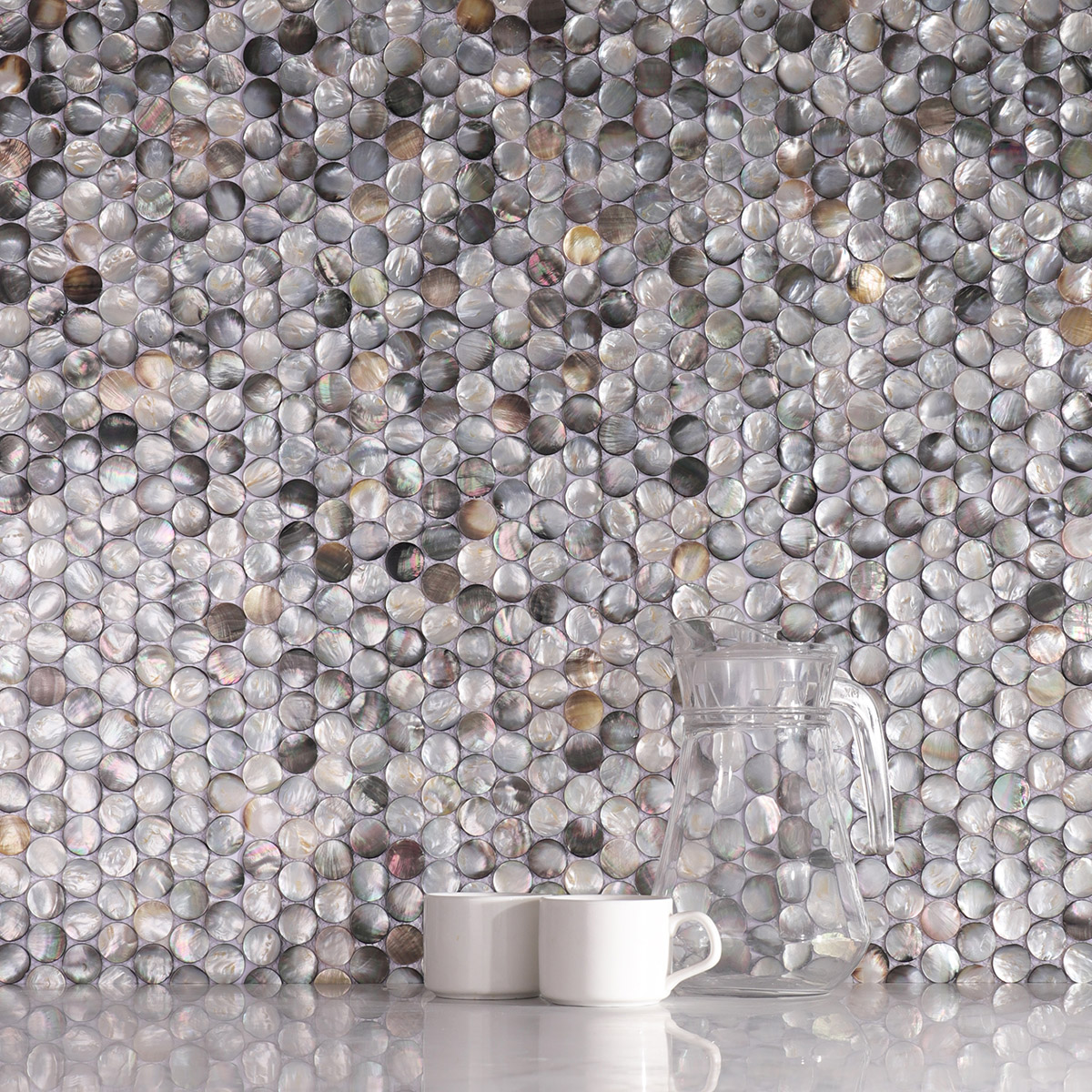Wall with black mother of pearl penny round tiles, two white cups on counter