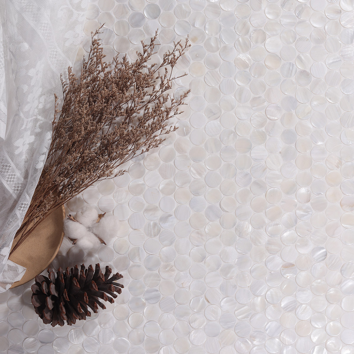 Penny round mother of pearl mosaic tiles with dried branches and gauze beside them