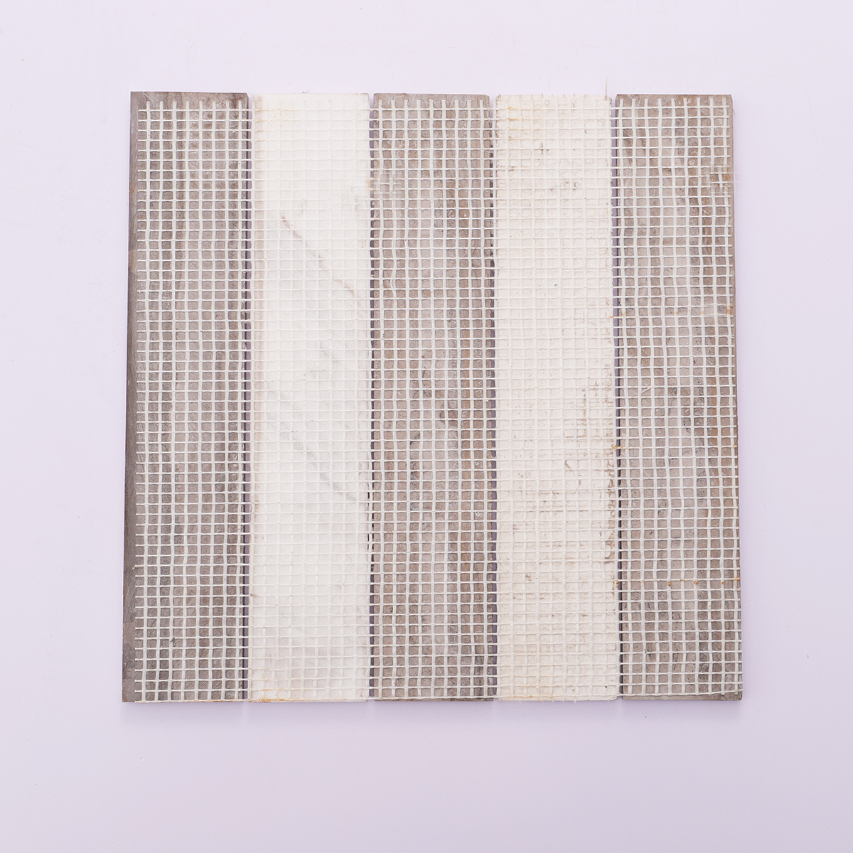 Back view of beige marble mosaic tiles showing mesh for easy installation