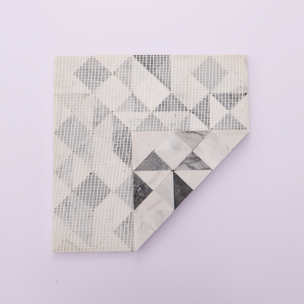 Back view with mesh backing of grey and white geometric triangle honed marble mosaic tiles.