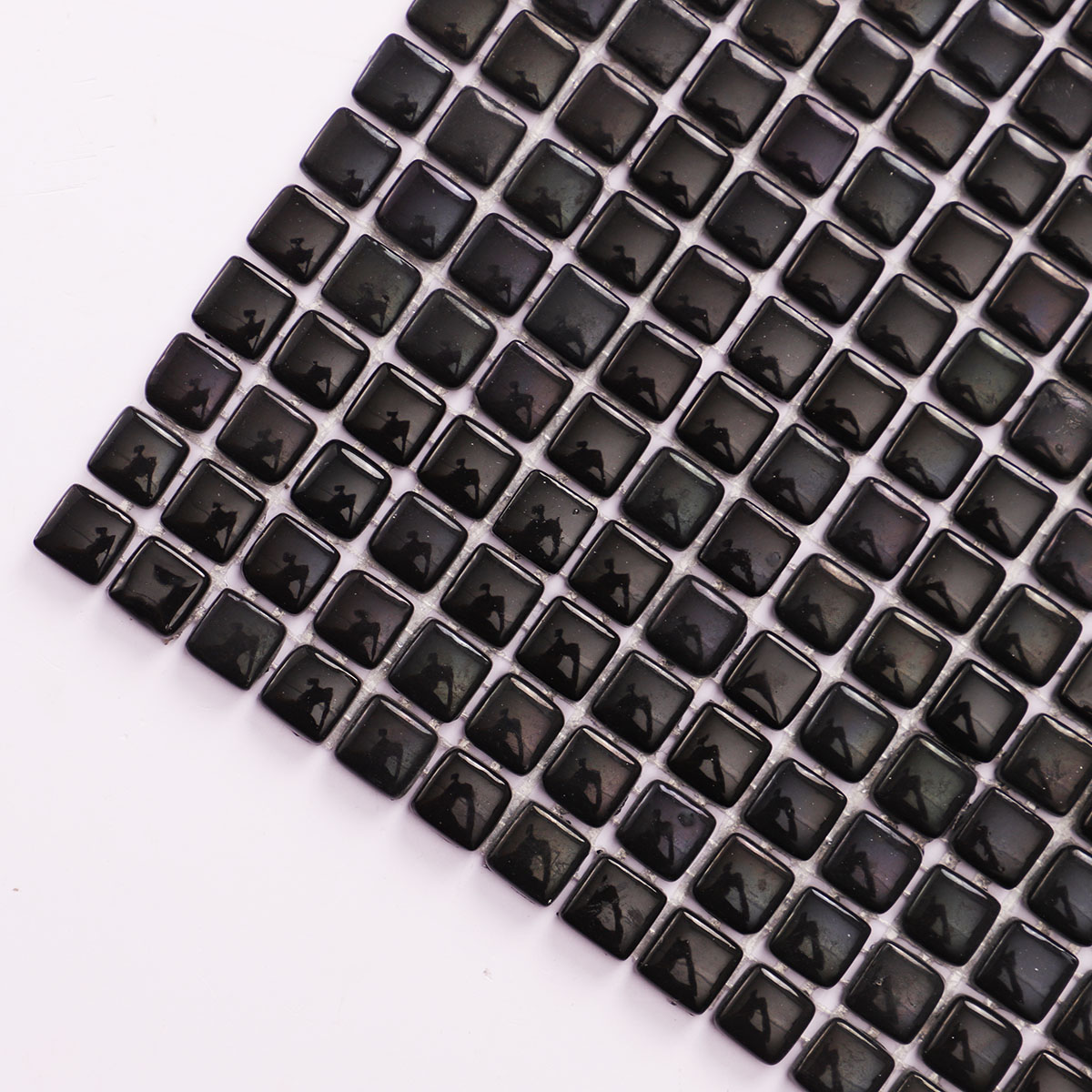 Macro close-up of tiny black glossy recycled glass mosaic tiles.