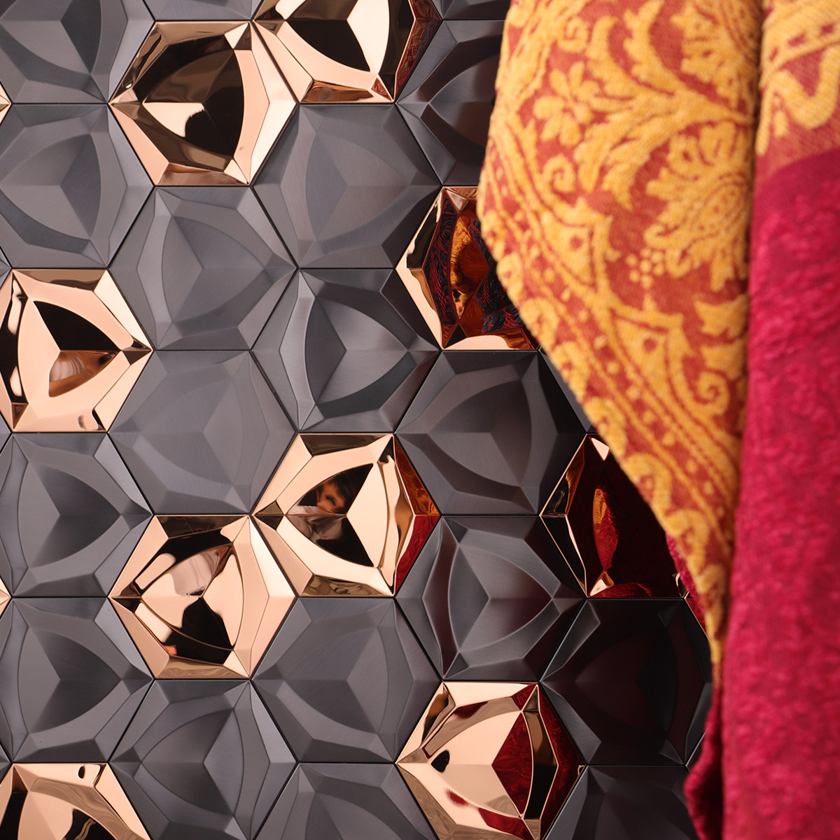 Close-up of 3D black and gold hexagon metal mosaic tiles with a curtain in the background.