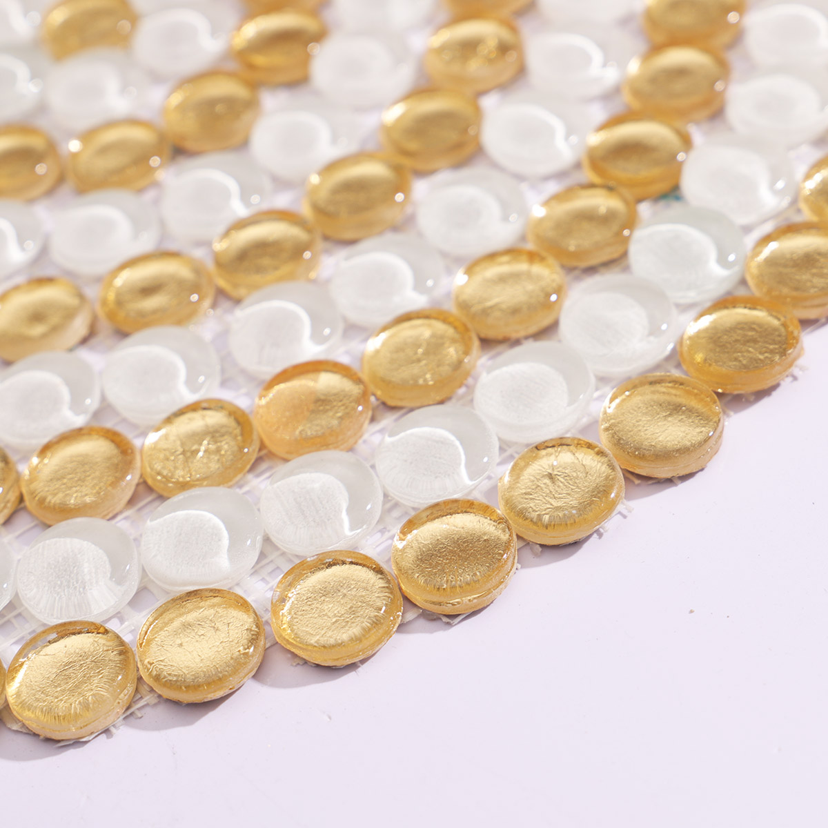 Side view of the circular gold and white mosaic tile, showing thickness