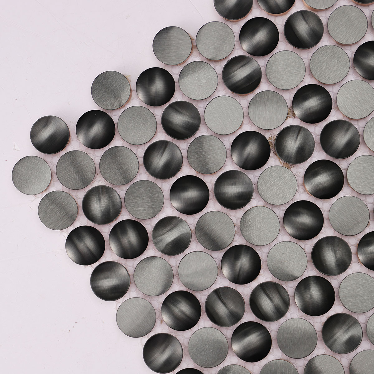 Close-up view of 3D black penny round metal mosaic tiles.