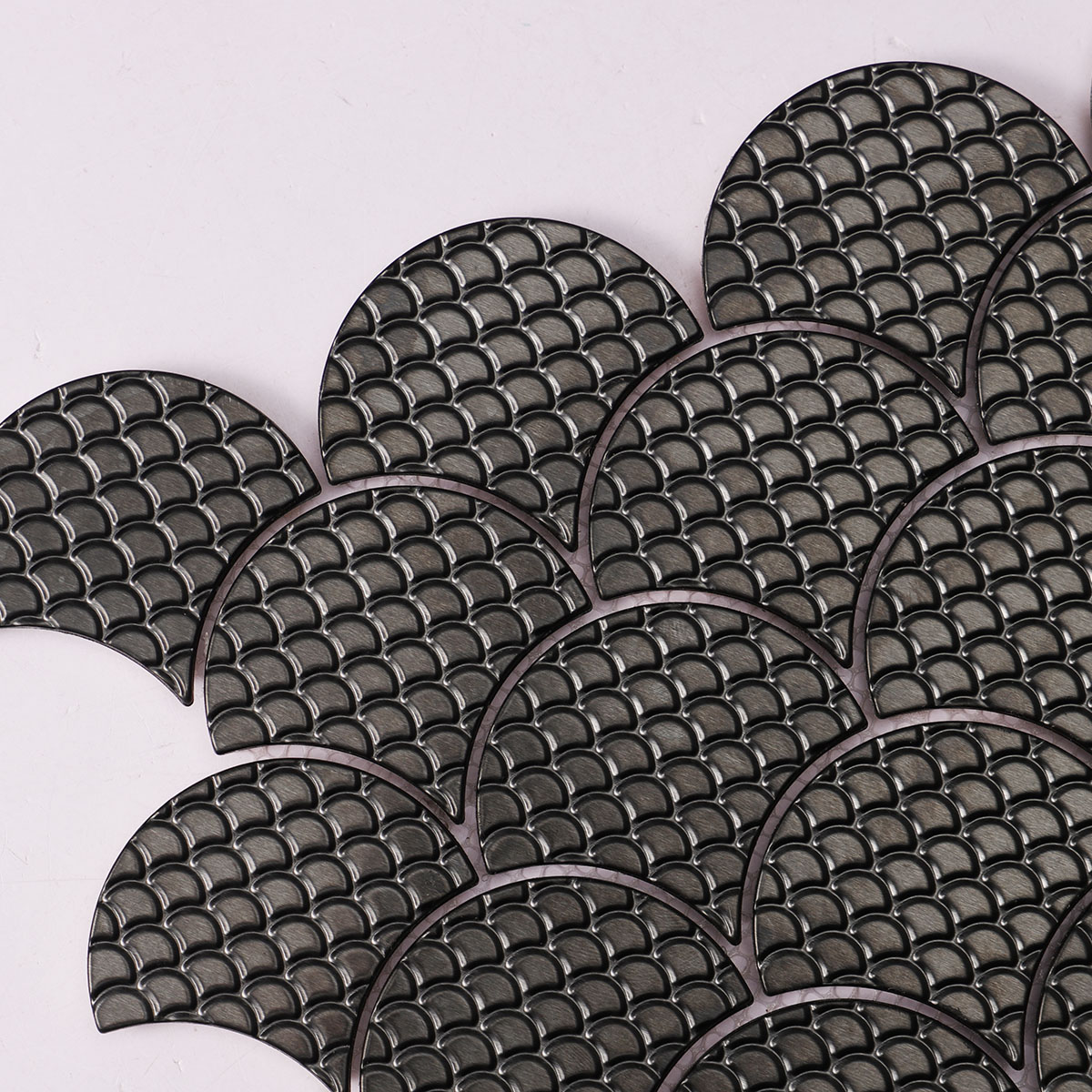 Macro close-up of black metal fish scale pattern mosaic tiles.