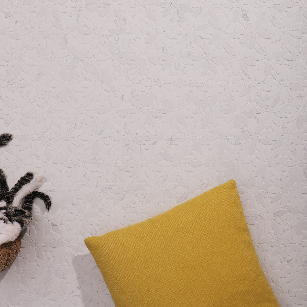 Daisy-patterned marble mosaic tile with yellow cushion and decorative items.