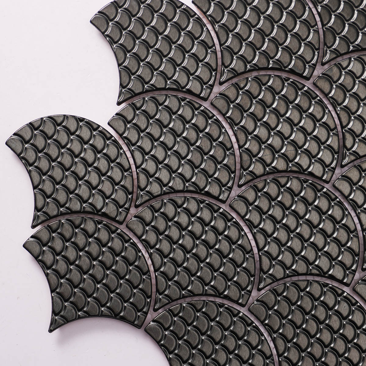 Close-up view of black metal fish scale pattern mosaic tiles.