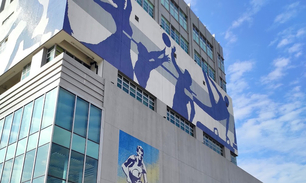 Mosaic mural above the front of the sports center depicting various athletic movements.