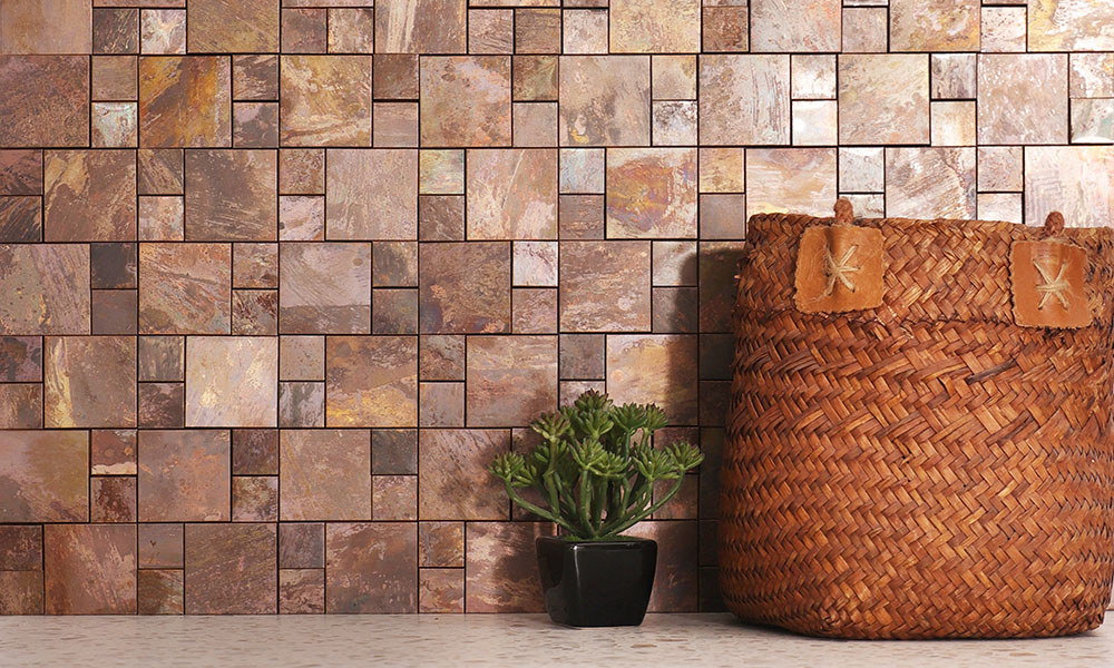 Square copper mosaic tiles on the wall with a small plant and a basket