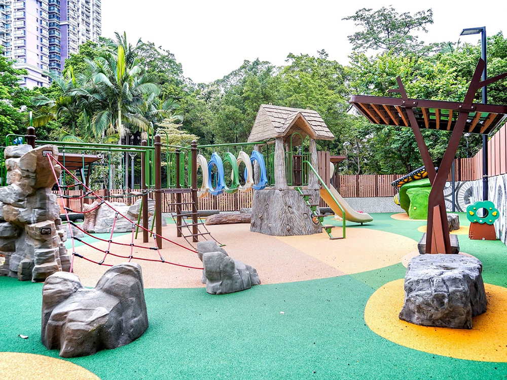 Children's area at Macau's Lu&iacute;s de Cam&otilde;es Garden, featuring colorful playground equipment and greenery.