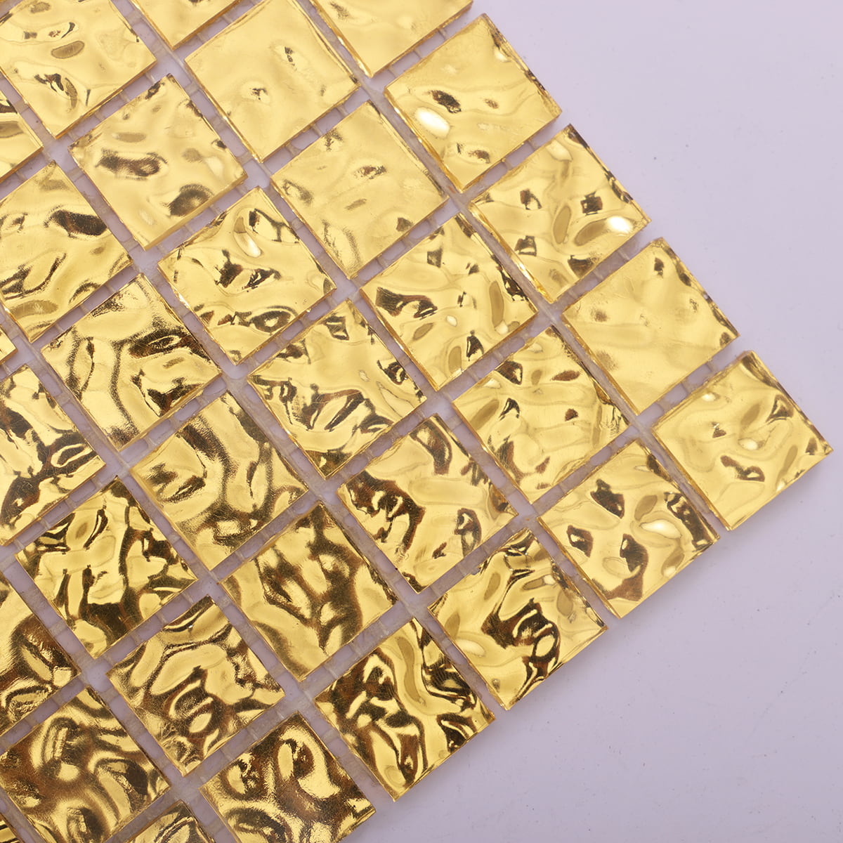 Close-up of 24K gold mosaic tiles with a wavy surface texture, perfect for luxurious design 