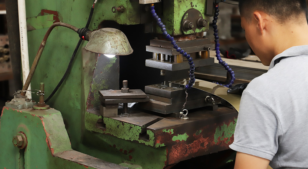 A worker pressing metal mosaic tiles.