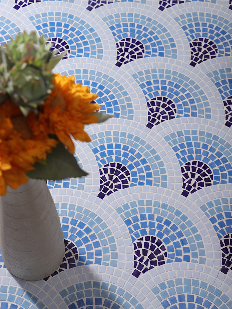 The blue and white fan-shaped mosaic tiles create an elegant pattern on the floor, beautifully complemented by a vibrant yellow flower bouquet, adding a cheerful touch to the space.