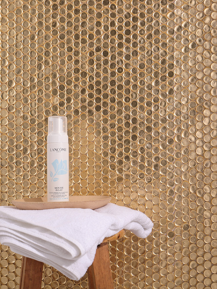 The gold round mosaic tiles on the bathroom wall add a luxurious touch, beautifully paired with neatly arranged toiletries for a polished look.