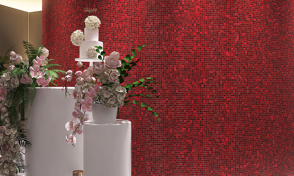 Red mosaic tiles on a curved wall with flower baskets in front.