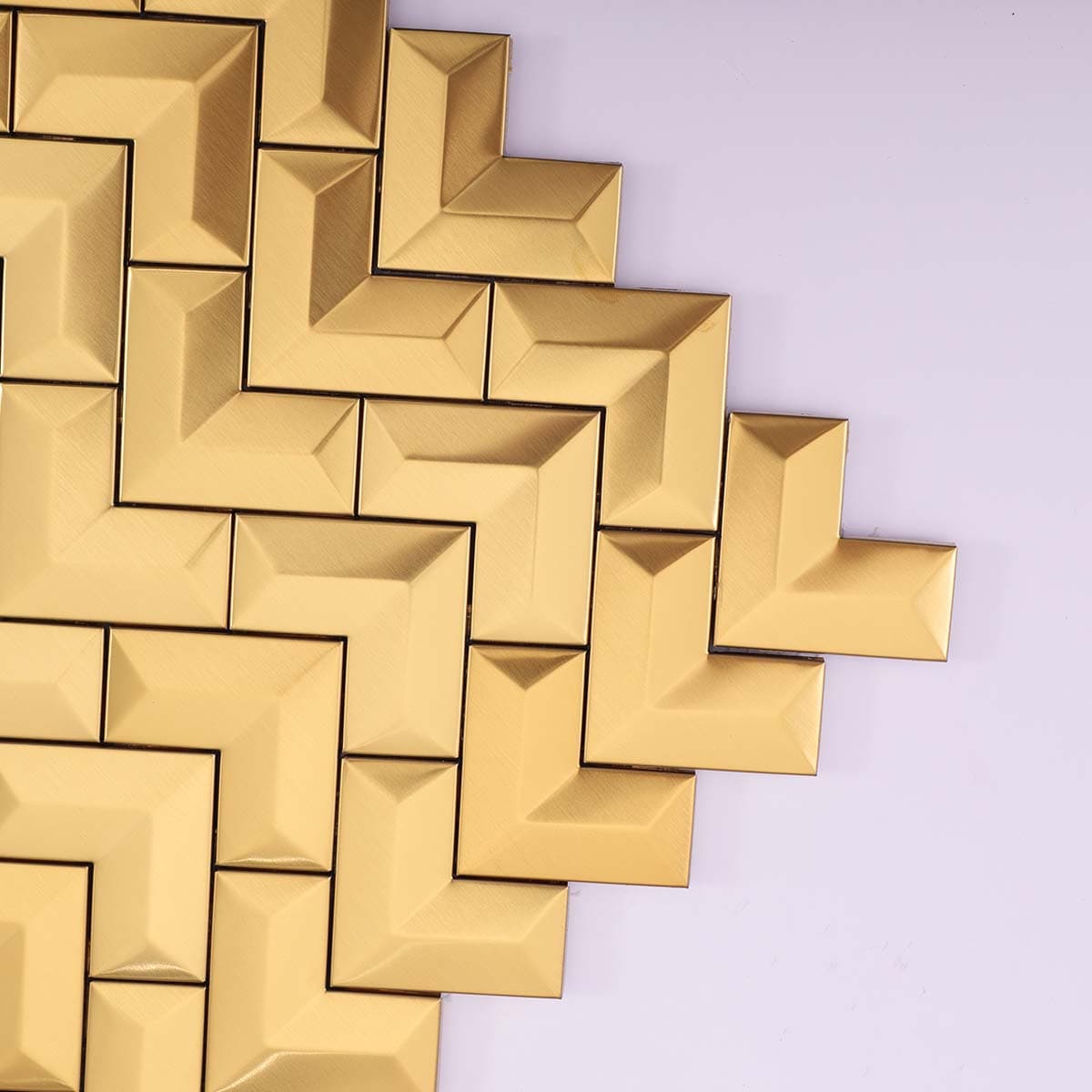 Corner close-up of 3D brushed gold stainless chevron tile