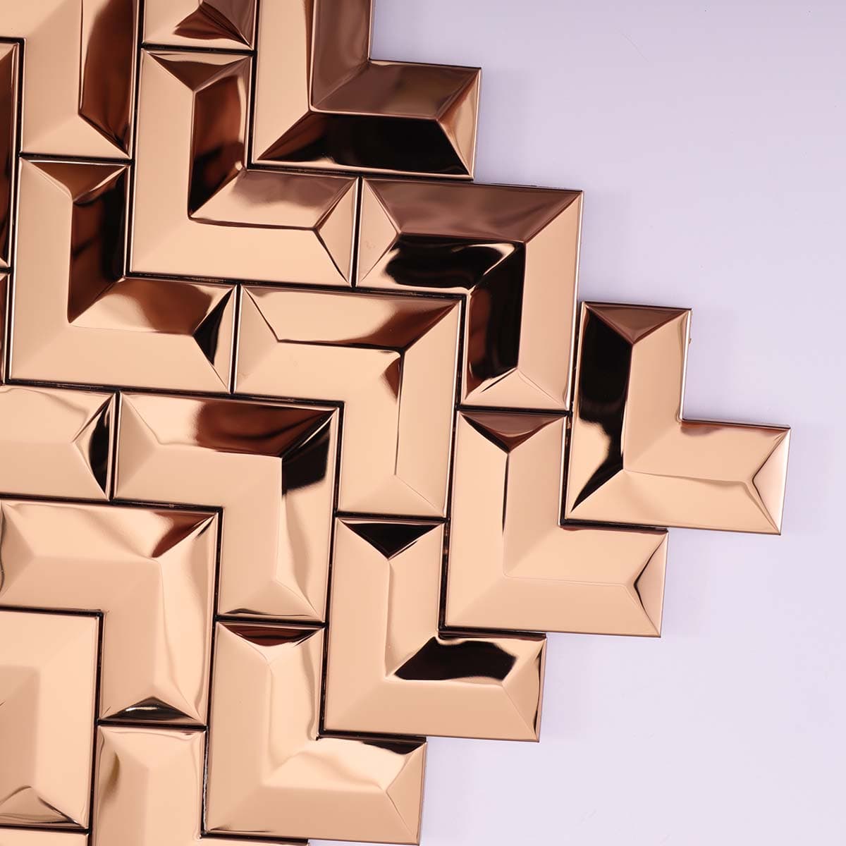 Corner close-up of glossy 3D rose gold stainless chevron tile