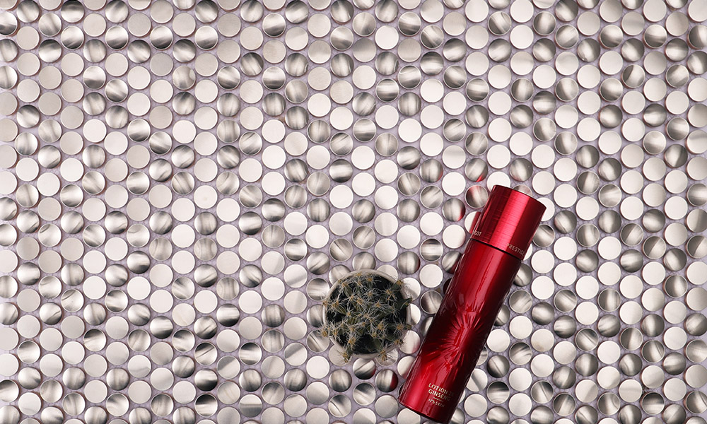 3D silver penny round mosaic tiles with a red cosmetic product.
