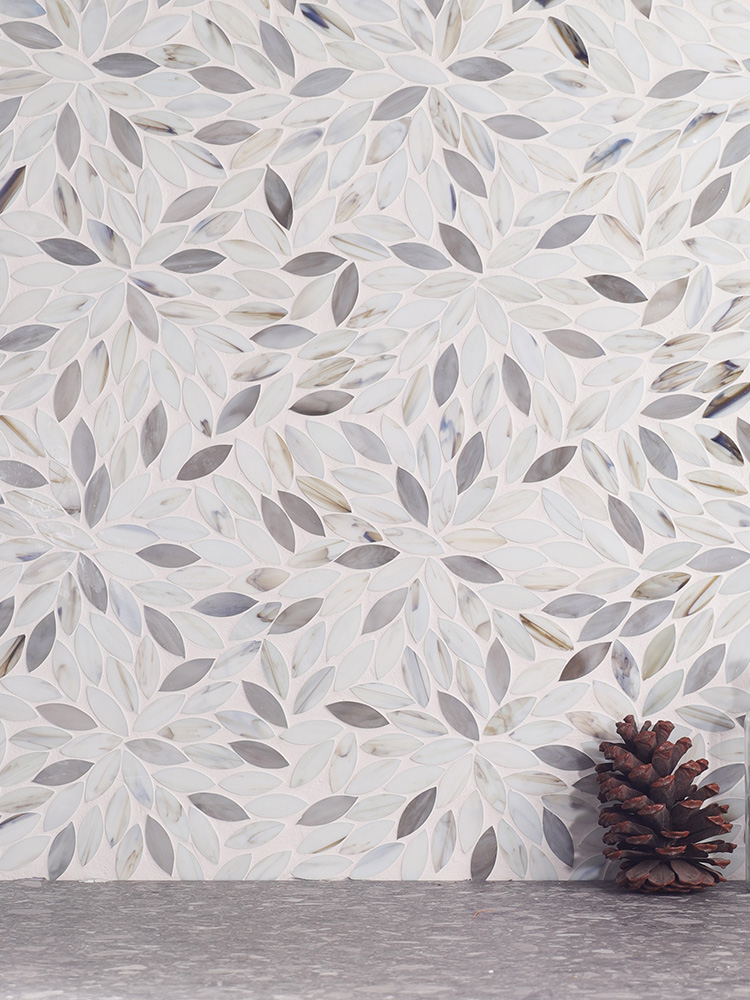 The white and light gray leaf-shaped mosaic tiles bring a delicate, nature-inspired touch to the wall, perfectly paired with sleek gray floor tiles for a harmonious look