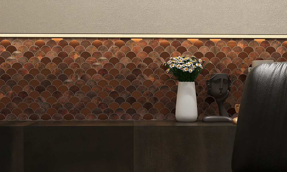 Fan copper mosaic tiles in a niche with a vase and a black bottle in front.
